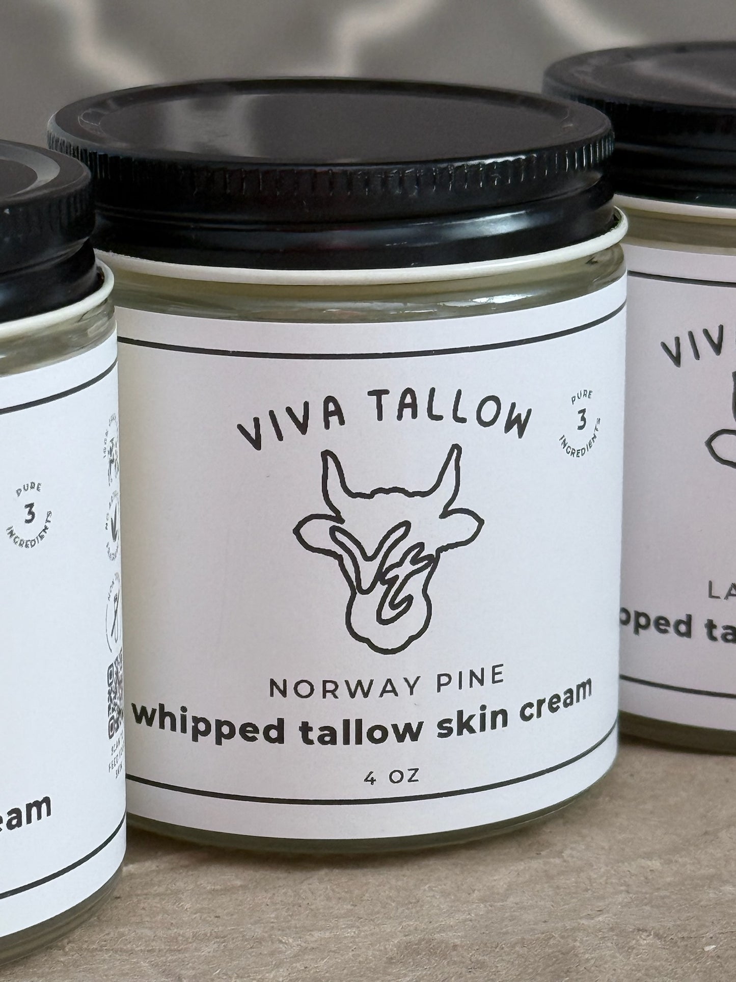 Jars of Viva Tallow Norway Pine whipped tallow skin cream on a neutral background
