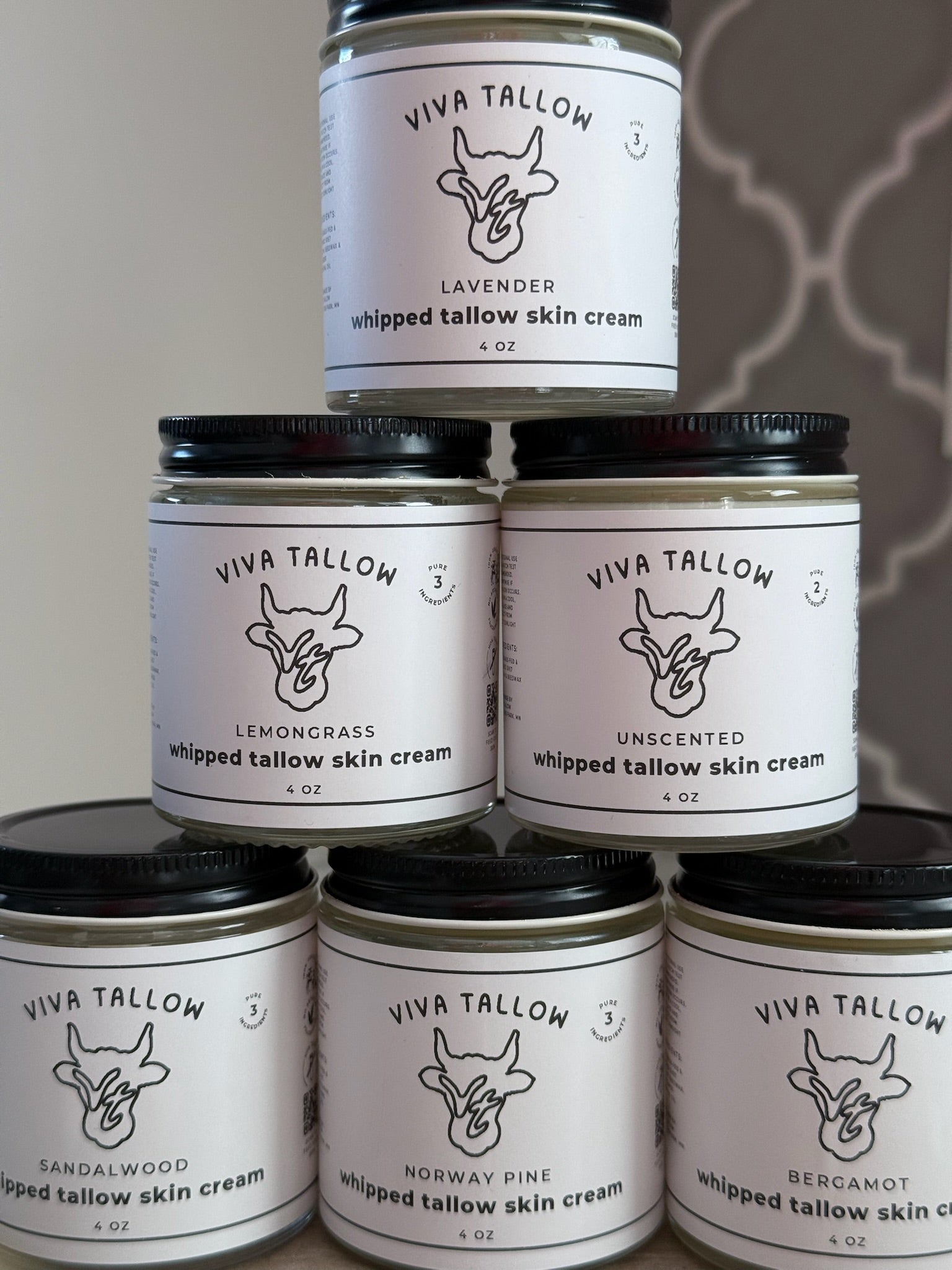 Stack of Viva Tallow whipped tallow skin cream jars with labels on a neutral background