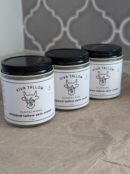 Four jars of Viva Tallow skin cream on a tiled surface with a decorative tile pattern in the background.